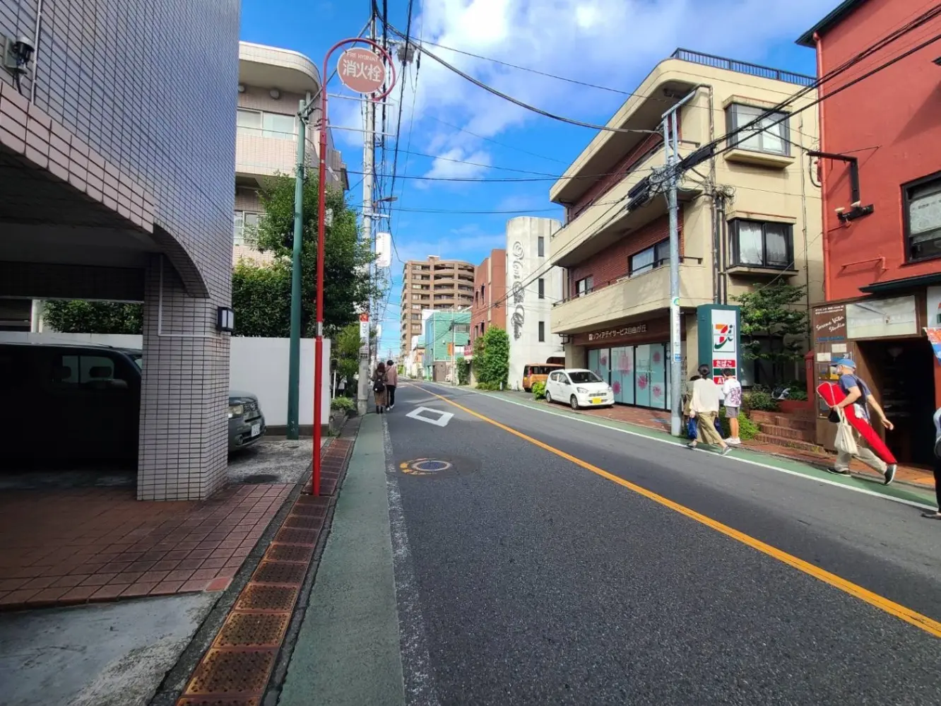 日本の都市の通りで歩行者や自動車が見られる日常風景、晴れた日の街並み