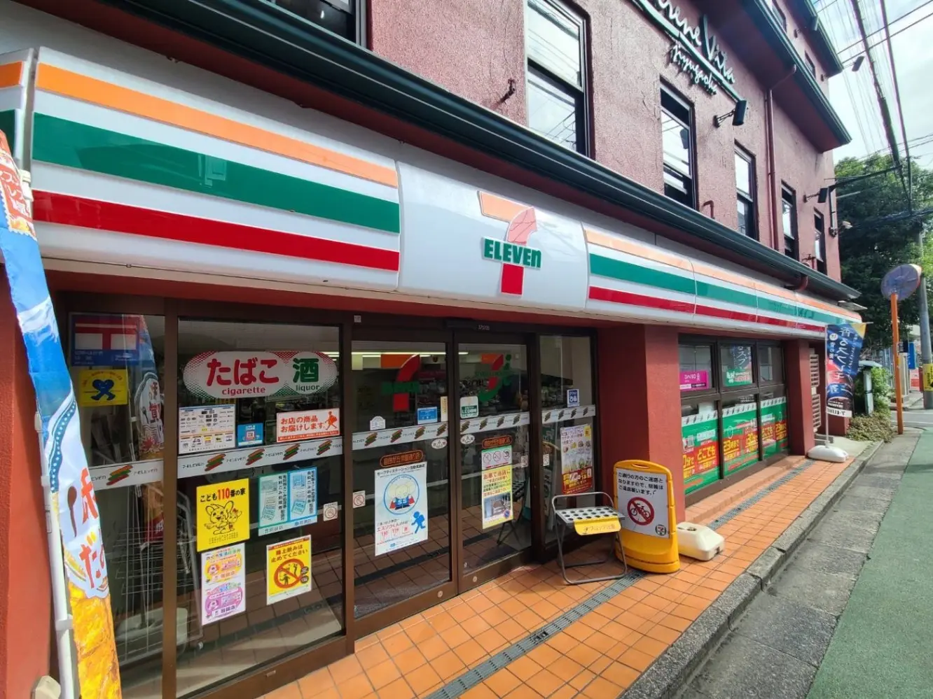 セブンイレブンの外観、店頭に掲示された様々な販促ポスター、便利なコンビニエンスストアの建物