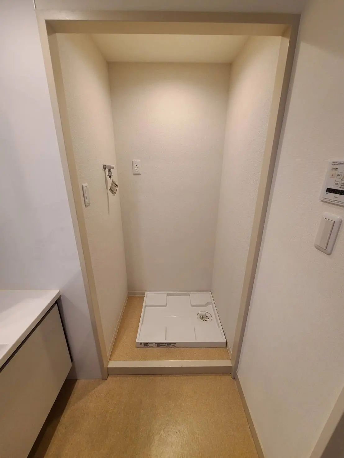 洗濯機置き場と収納棚が設置された洗面室、クリーム色の壁と床デザイン