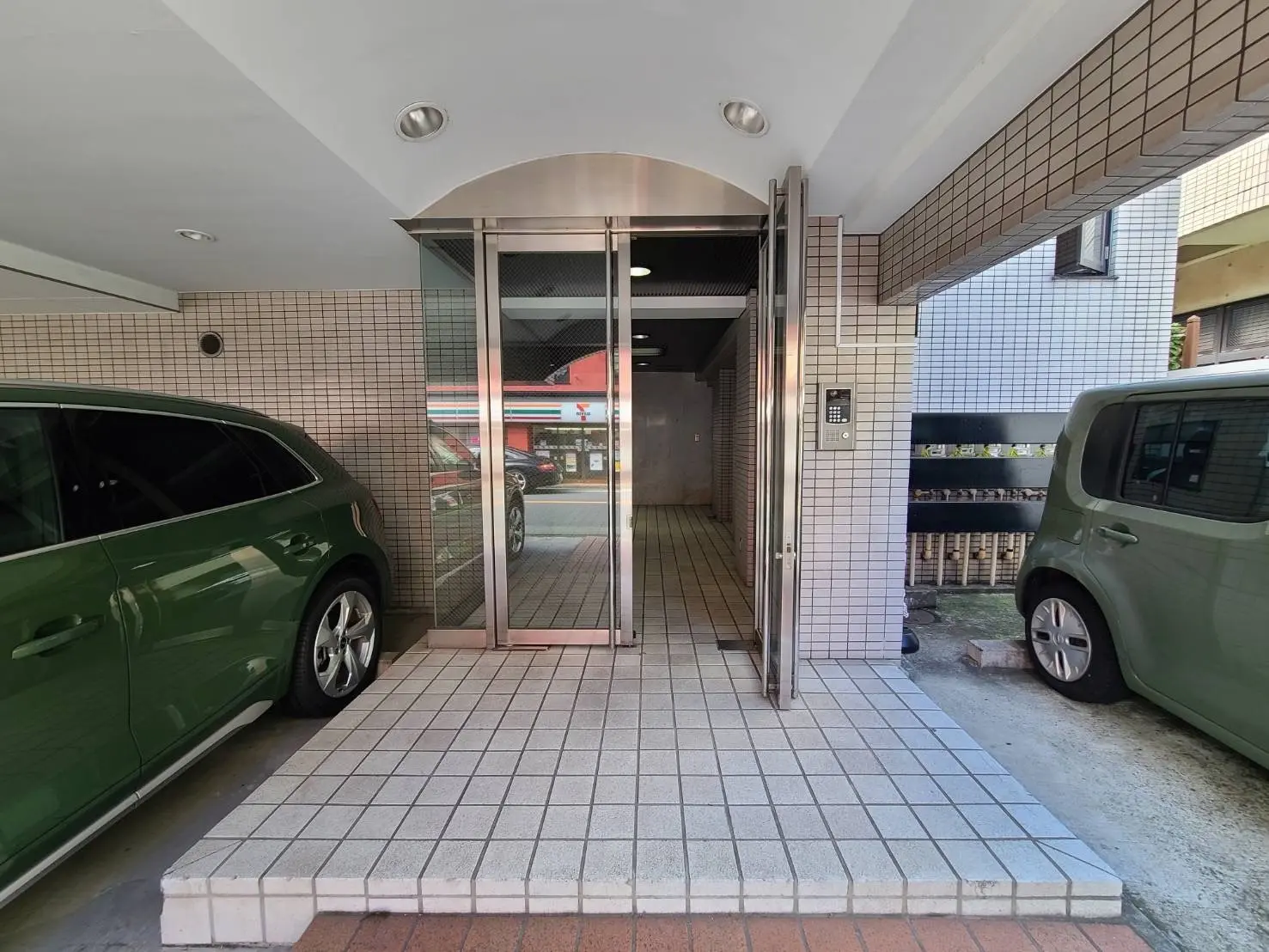 駐車場入り口の写真、スライド式自動ドア、タイル壁、電気自動車充電器付き，都市生活の便利なアメニティ