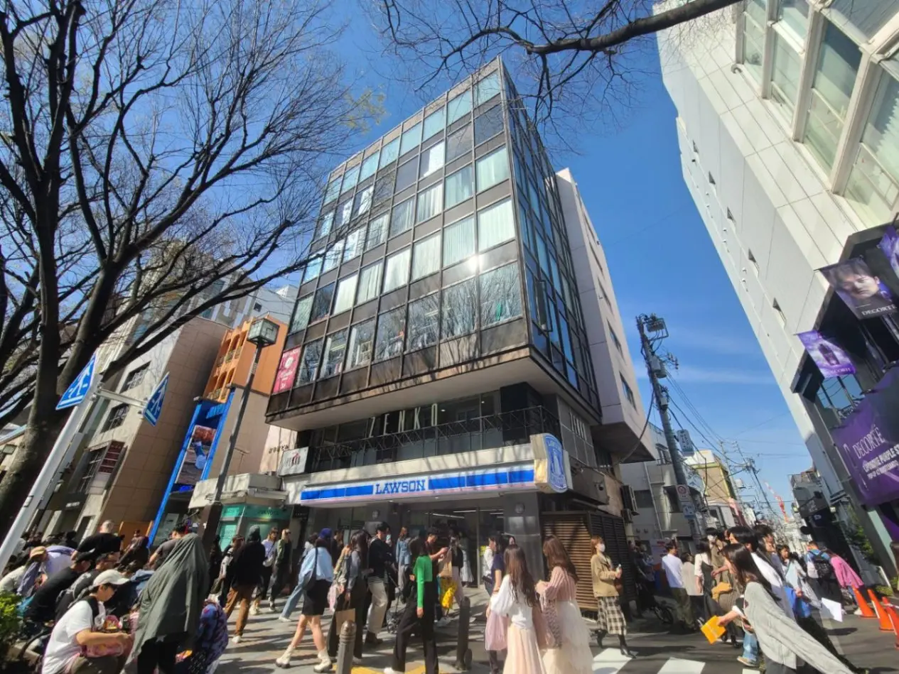 都会の賑やかな通りで様々な人々が歩く風景、晴れた日の青空、建物と店舗の外観