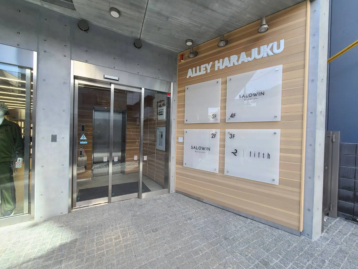 原宿のモダンな商業ビル「ALLEY HARAJUKU」のエントランスとテナント看板、クリアなガラスドア