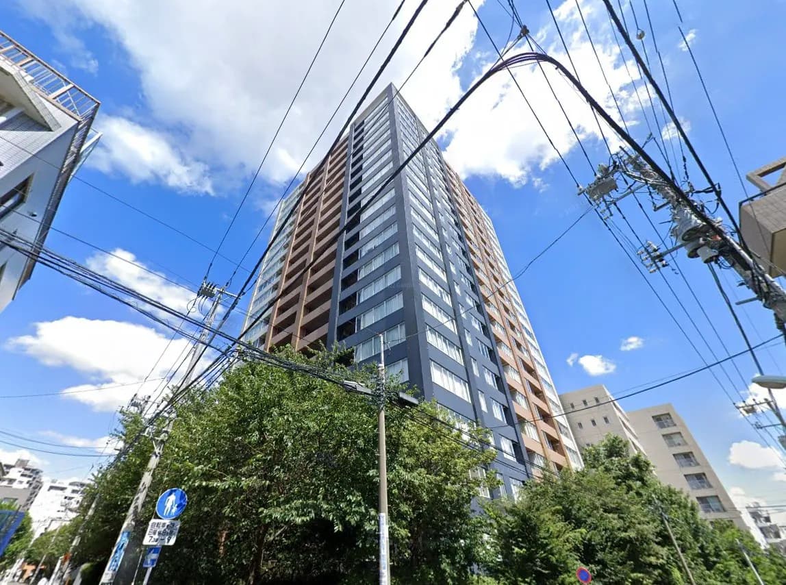 現代的な高層マンションの外観、青空と雲、周囲の緑と都市の電線