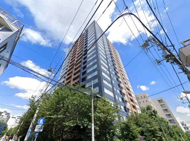 現代的な高層マンションの外観、青空と雲、周囲の緑と都市の電線