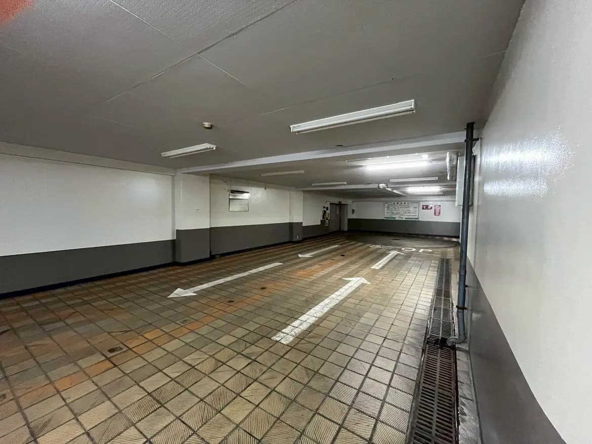 - 明るい照明が当たる清潔な地下駐車場、矢印の案内サインが表示された広々としたスペース