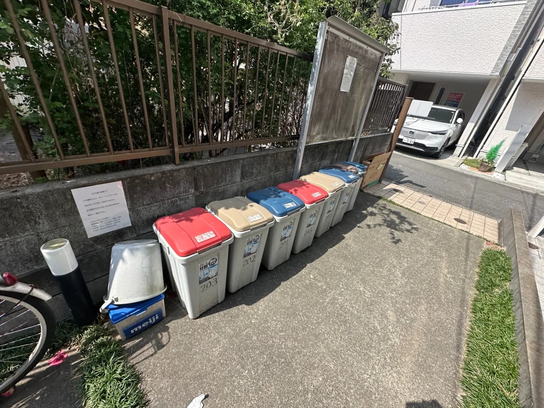 日本のマンションのゴミ出し場、分別用の色分けされたゴミ箱とリサイクルボックスが並ぶ外観