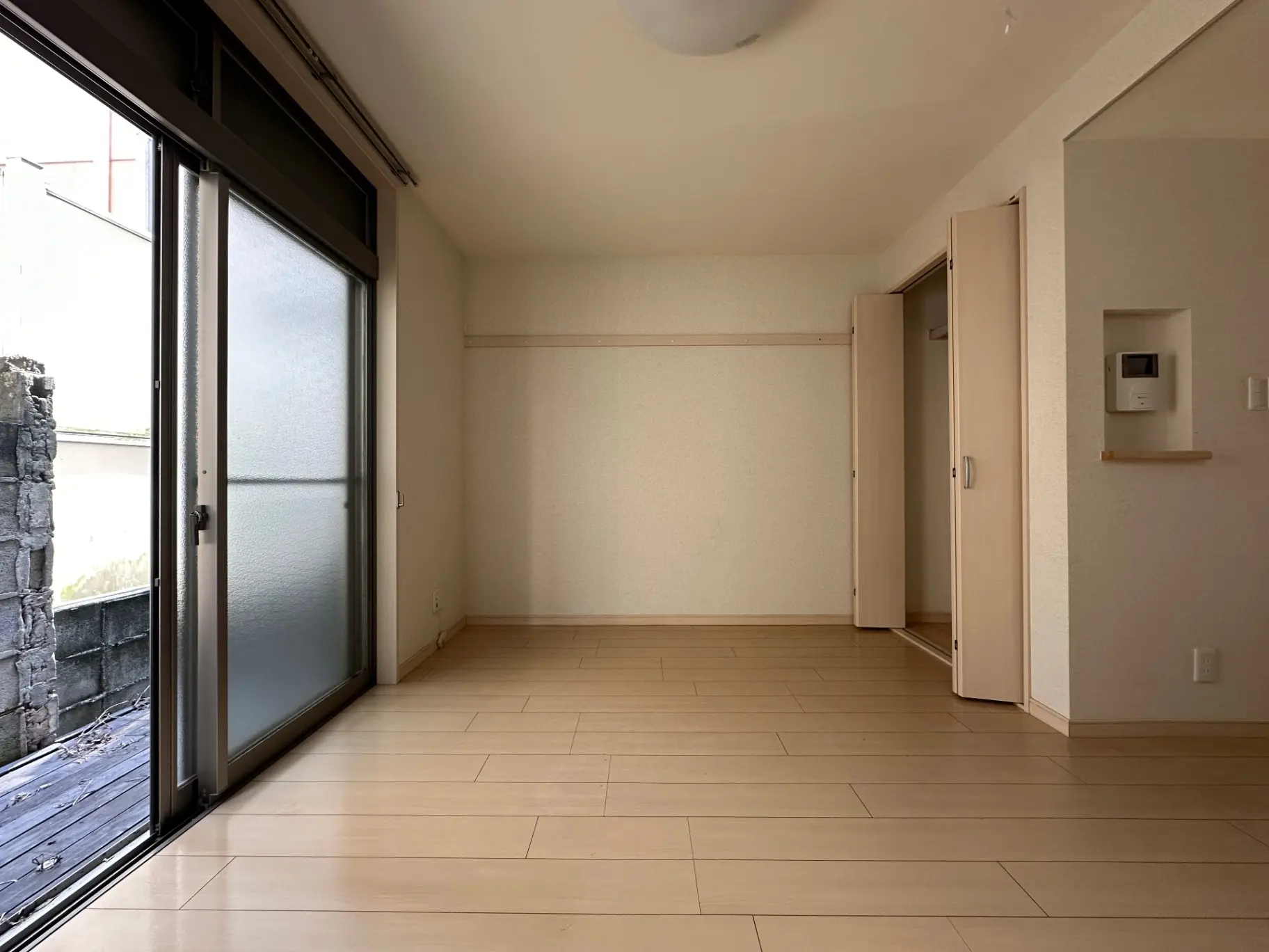 明るく広々とした和風の空き部屋、掃出し窓と和室の木製フロア、収納付きのインテリア