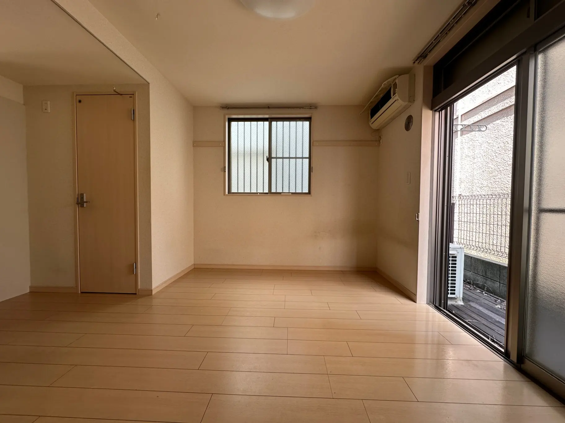 広々とした空の部屋、明るいタイルフローリング、窓から自然光が差し込むリビングルーム