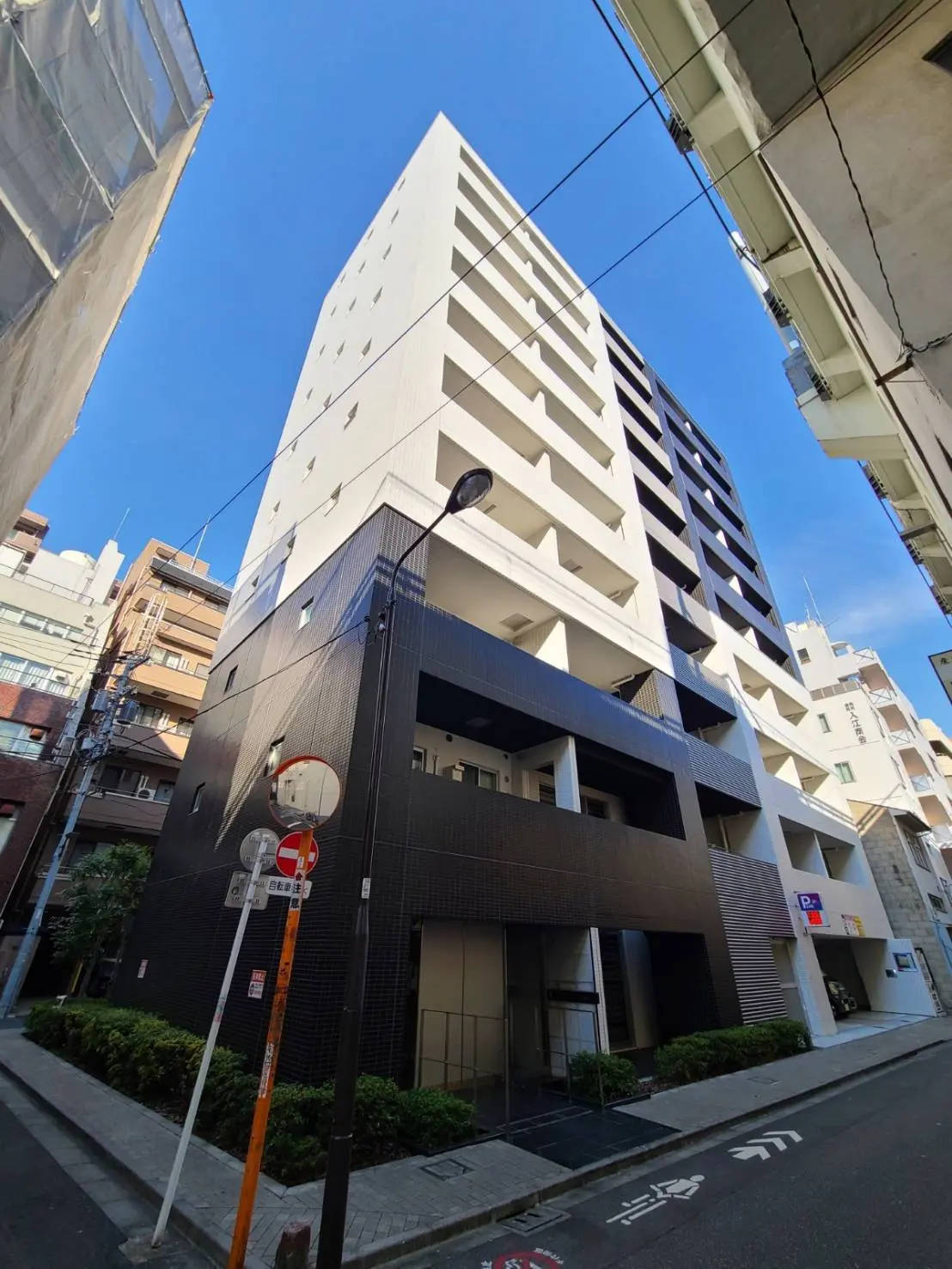 都市の路地にあるモダンな白と黒のマンション、駐車スペースあり、晴天の下での外観