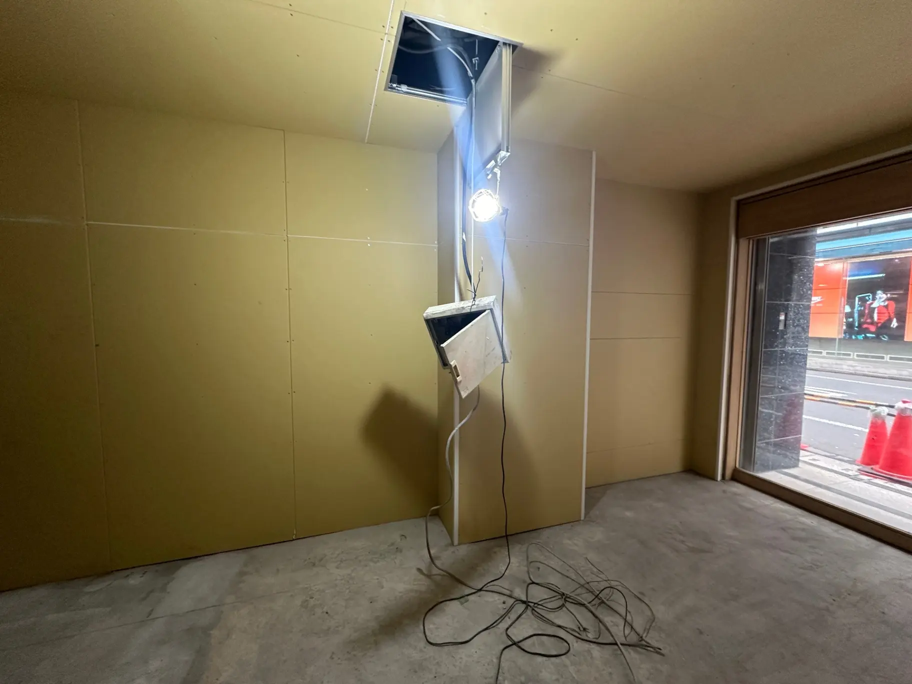 工事中の室内、壁には未完成のボードが取り付けられており、床には電線が散乱している状態