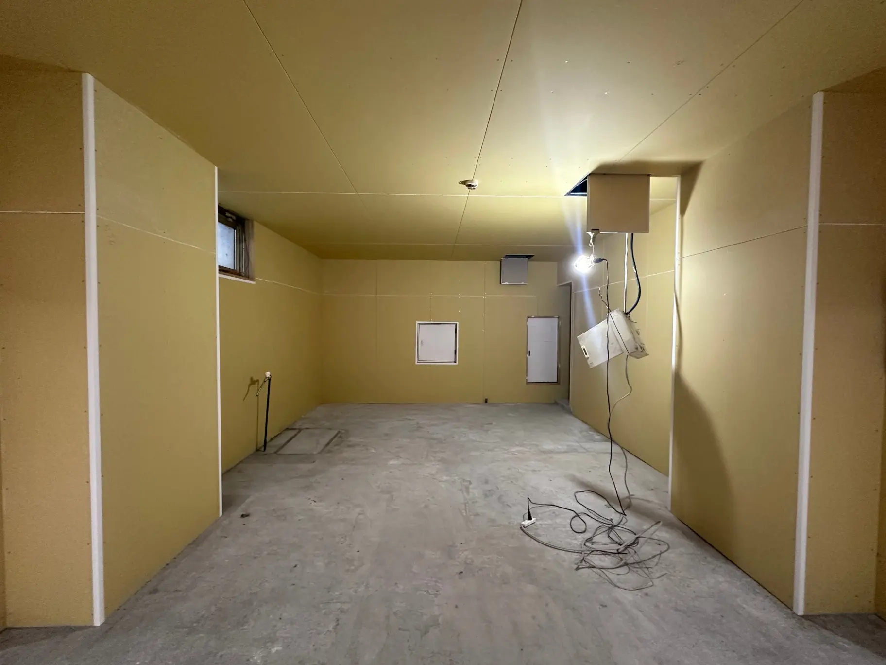未完成の建物の内部、コンクリートの床と黄色の壁、配線が露出している状態