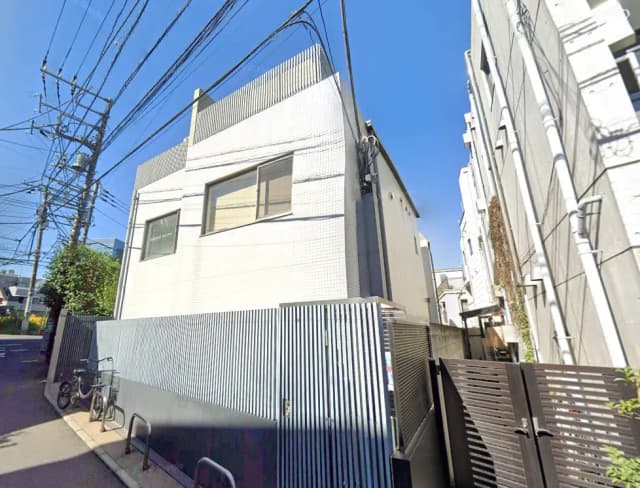 都市部にあるモダンな白い建物の外観、青い空と周囲のビルに囲まれた景色