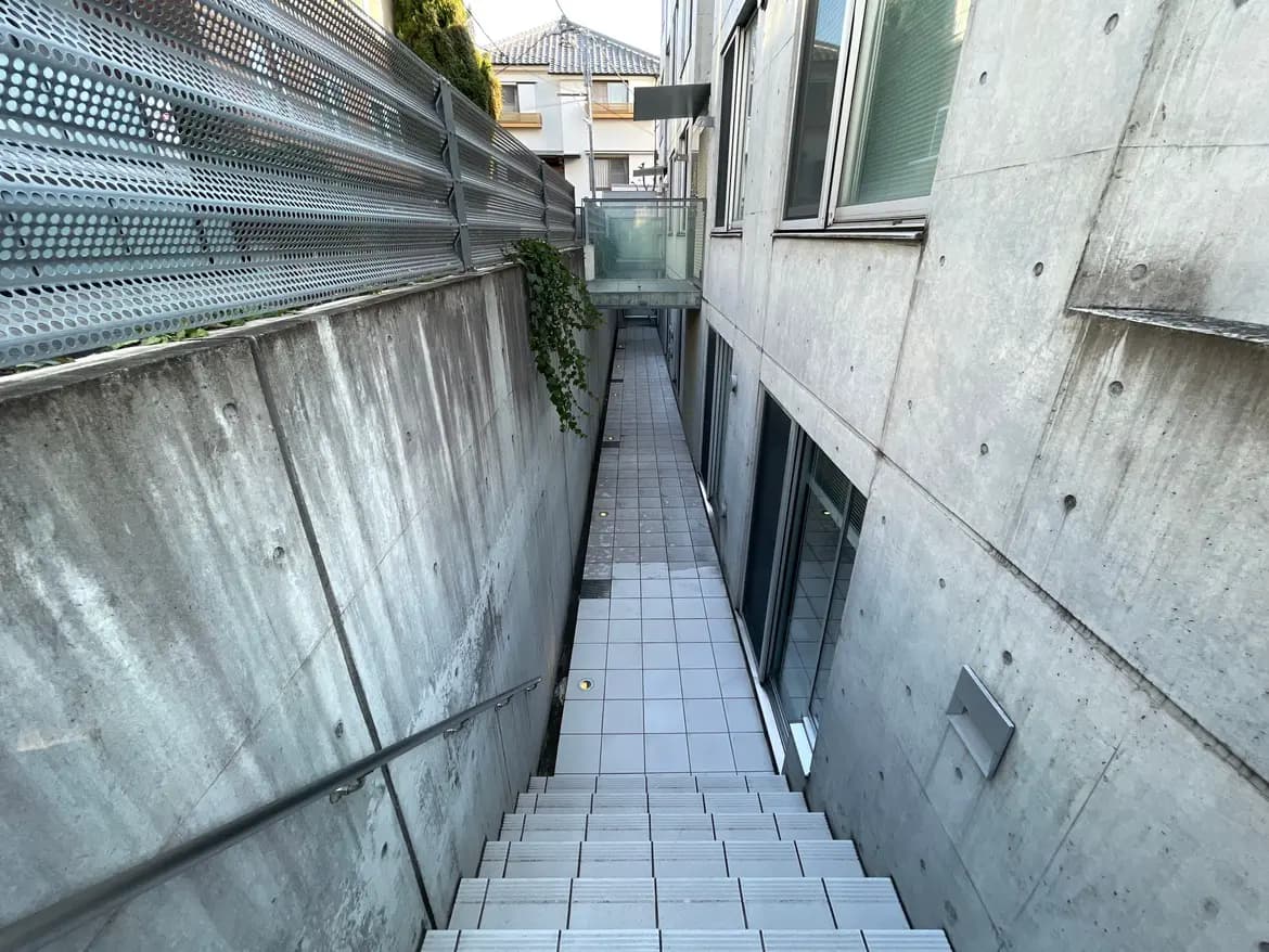 都会的な建物間の狭い通路、コンクリートと金属フェンスが特徴的なモダンなデザイン