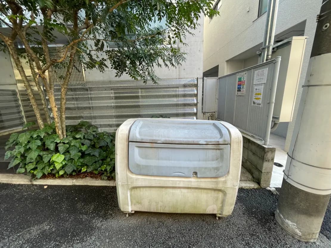 廃棄された白い冷蔵庫が建物の隣に置かれている、都市の不用品回収エリア