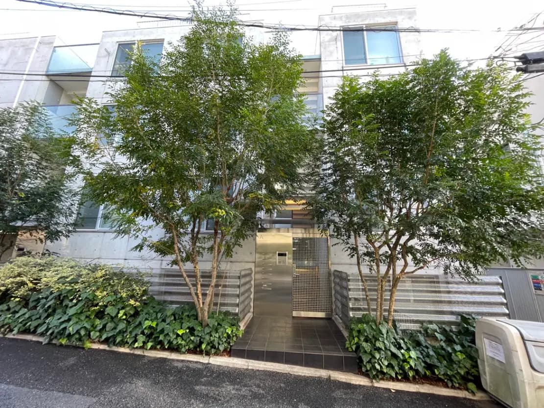 都会の緑豊かなモダンなアパートの入り口、木々と植栽が美しい外観