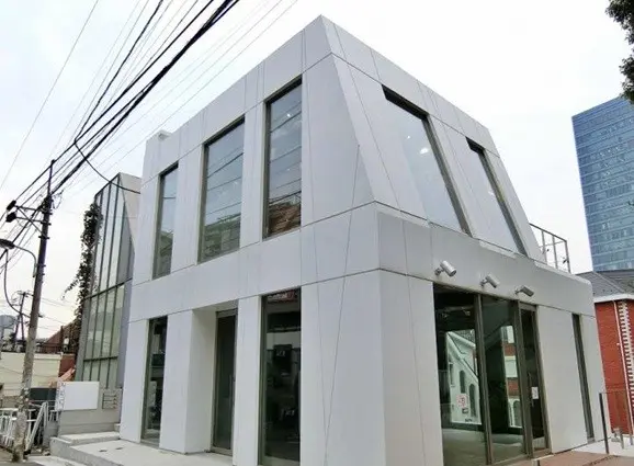 - 近代的なデザインの商業ビル、白い外観と大きな窓が特徴のファサード、周辺の都市景観と調和した建物