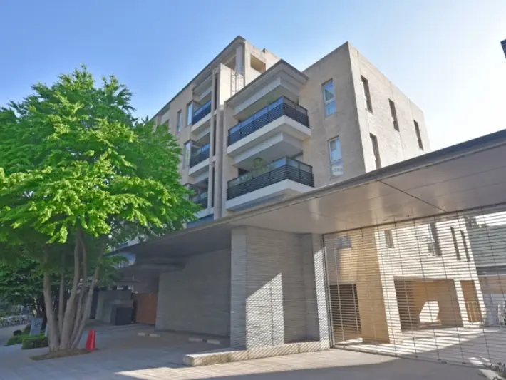都市風景のモダンなマンション、緑豊かな樹木と明るい日差しが注ぐエントランス