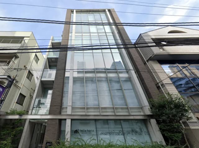- 現代的なファサードを持つビル、ガラスとレンガを使用したデザイン、街中の一角に位置する不動産会社の外観