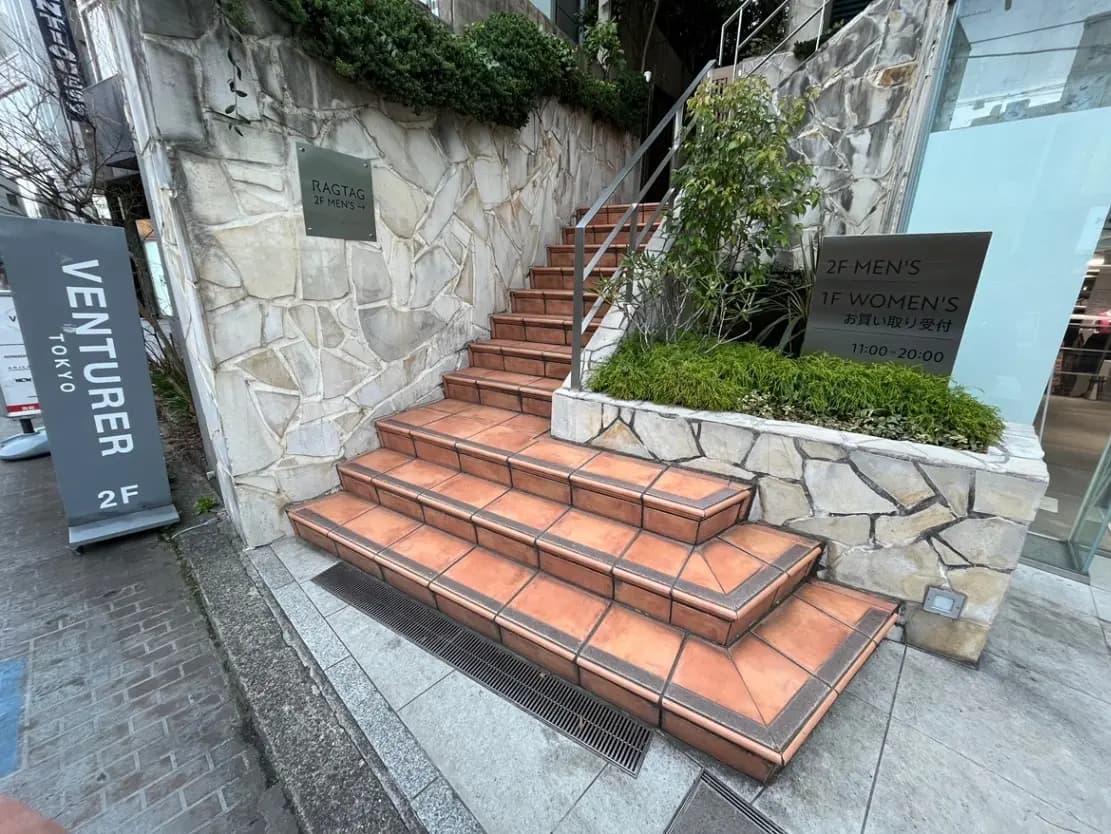- 東京の店舗入口、階段と案内看板、2階は男性用、1階は女性用の表示があるショッピングエリアの外観