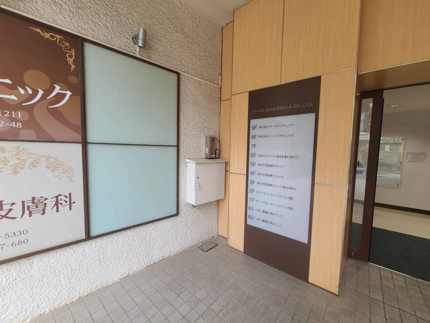 - 新赤坂ビルの入口、ビル名が表示された看板と周辺のインテリア、郵便受けのあるシンプルな外観