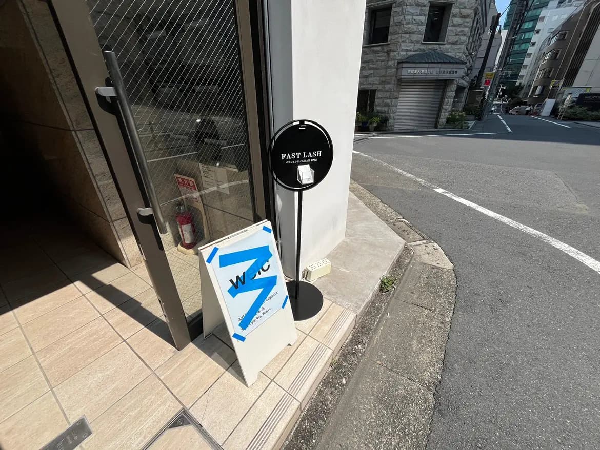 - おしゃれな美容サロン「FAST LASH」の看板と入口、周囲の街並みが見える風景