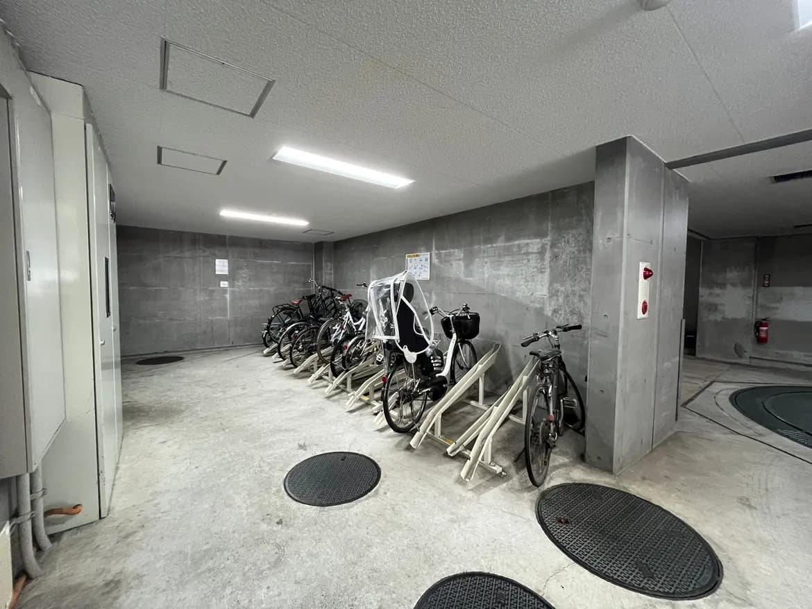 - コンクリート製の壁と床の自転車専用駐輪場、整理された自転車と明るい照明が特徴の空間