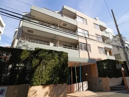 - 現代的な外観のマンション、シンプルなデザインと緑豊かな植栽が特徴、周囲の街並みが映える風景