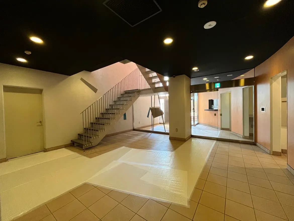 - 現代的なデザインのエントランスホール、白い床と階段、天井の黒い照明が特徴の広々とした空間