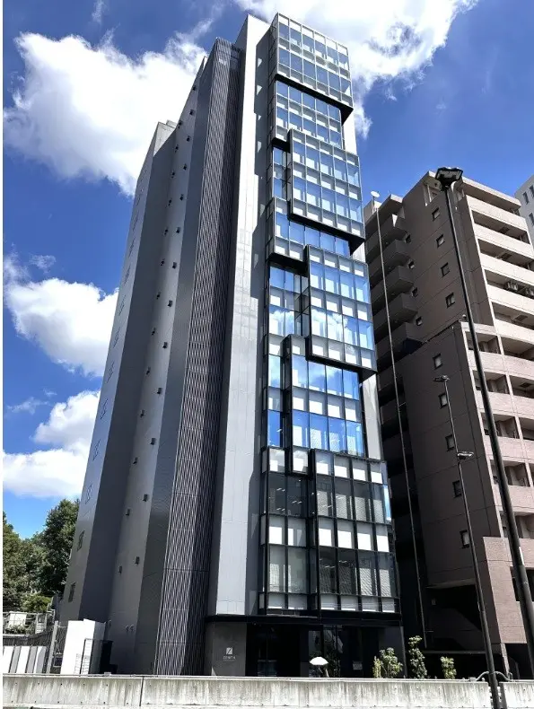 現代的なデザインの高層ビル、ガラスのファサードとメタリックな外壁が特徴、青空を背景にした都市風景