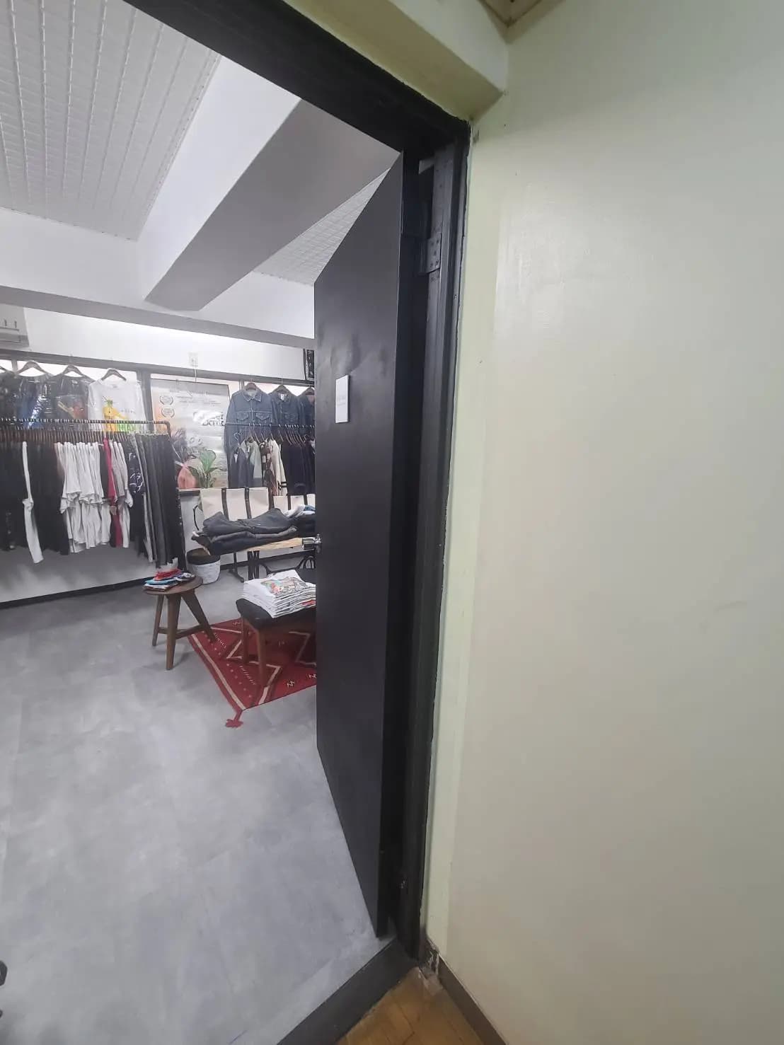 - 店内の黒いドア越しに見える衣類が並んだクローゼット、スタイリッシュなインテリア空間の一部