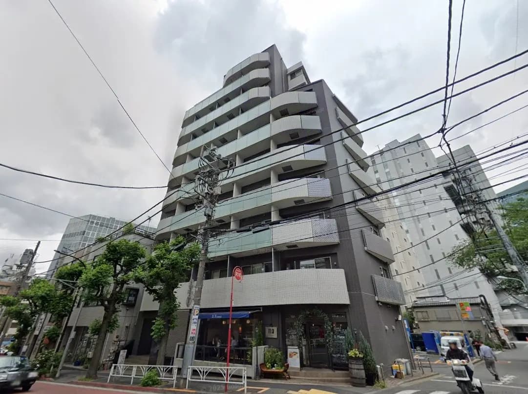 - 近代的なデザインのマンション外観、グレーのタイルとバルコニー、周囲の緑とモダンな都市風景が広がる景観