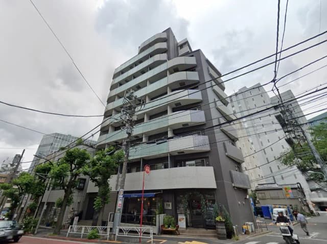 - 近代的なデザインのマンション外観、グレーのタイルとバルコニー、周囲の緑とモダンな都市風景が広がる景観