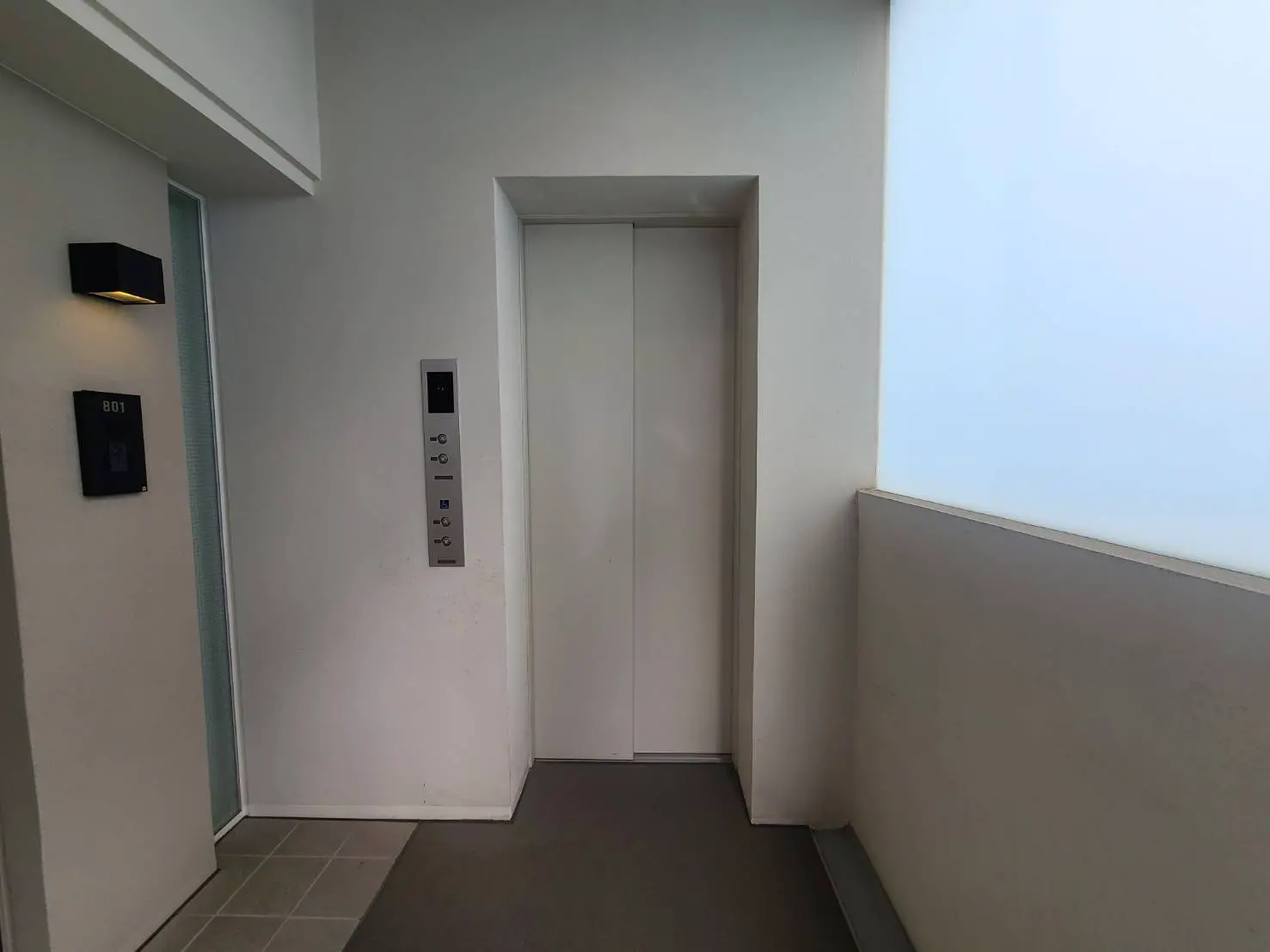 - モダンなエレベーターの前の廊下、シンプルな壁と明るい照明、部屋番号801のプレートがあるインテリア