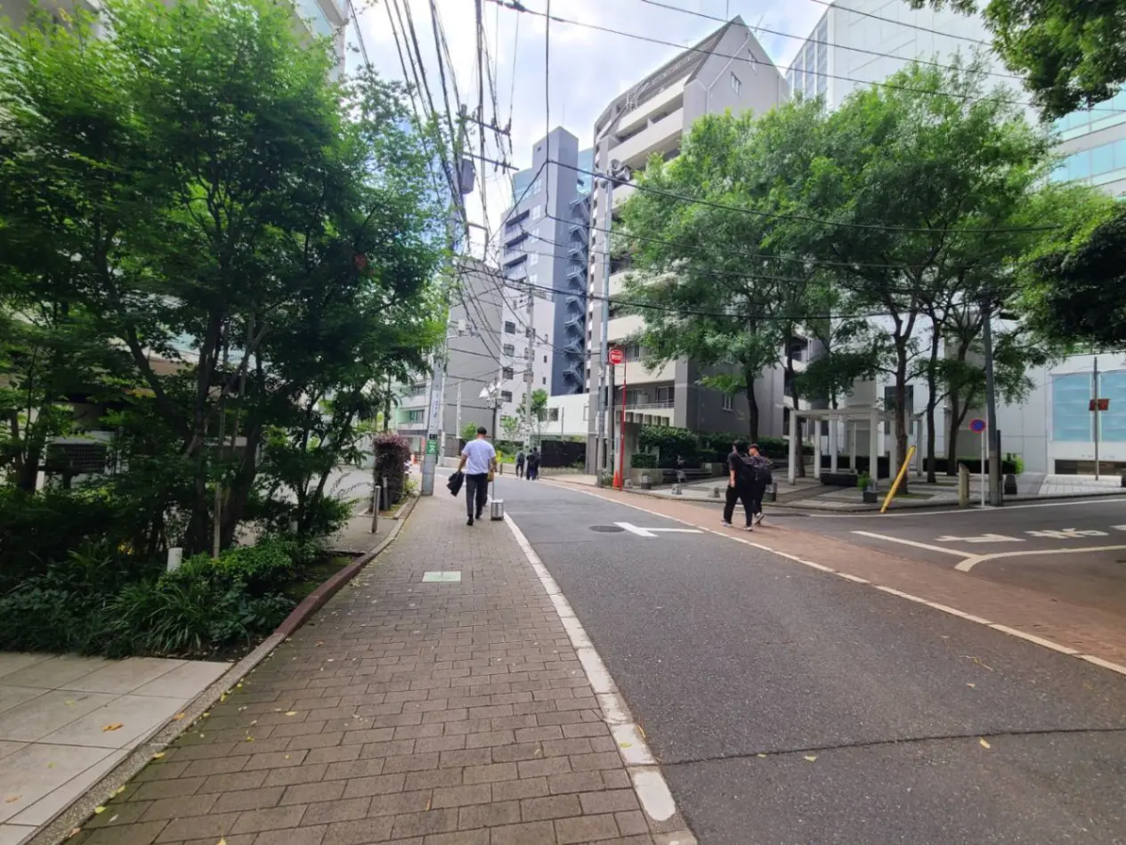 - 植栽とビルが立ち並ぶ都会の街道、歩道を歩く人々と周囲の緑が調和した風景