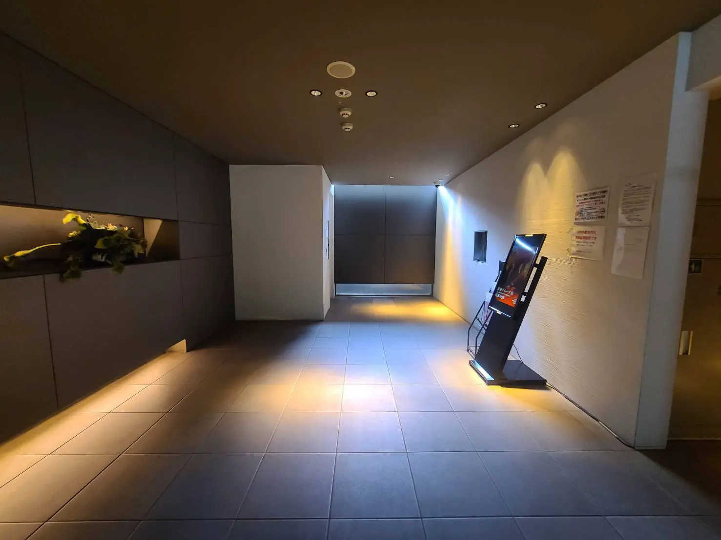 - モダンなデザインのロビー、落ち着いた照明、壁に埋め込まれた植物のディスプレイが特徴の空間