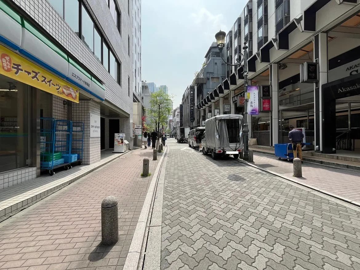 - 都市の歩道と車道、飲食店の看板が掲げられたビルの側面、人々が行き交う賑やかな街並み