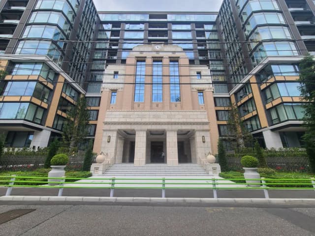 - モダンな高層マンションとクラシックなデザインのエントランス、整備された植栽とシンプルな階段が特徴の建物外観