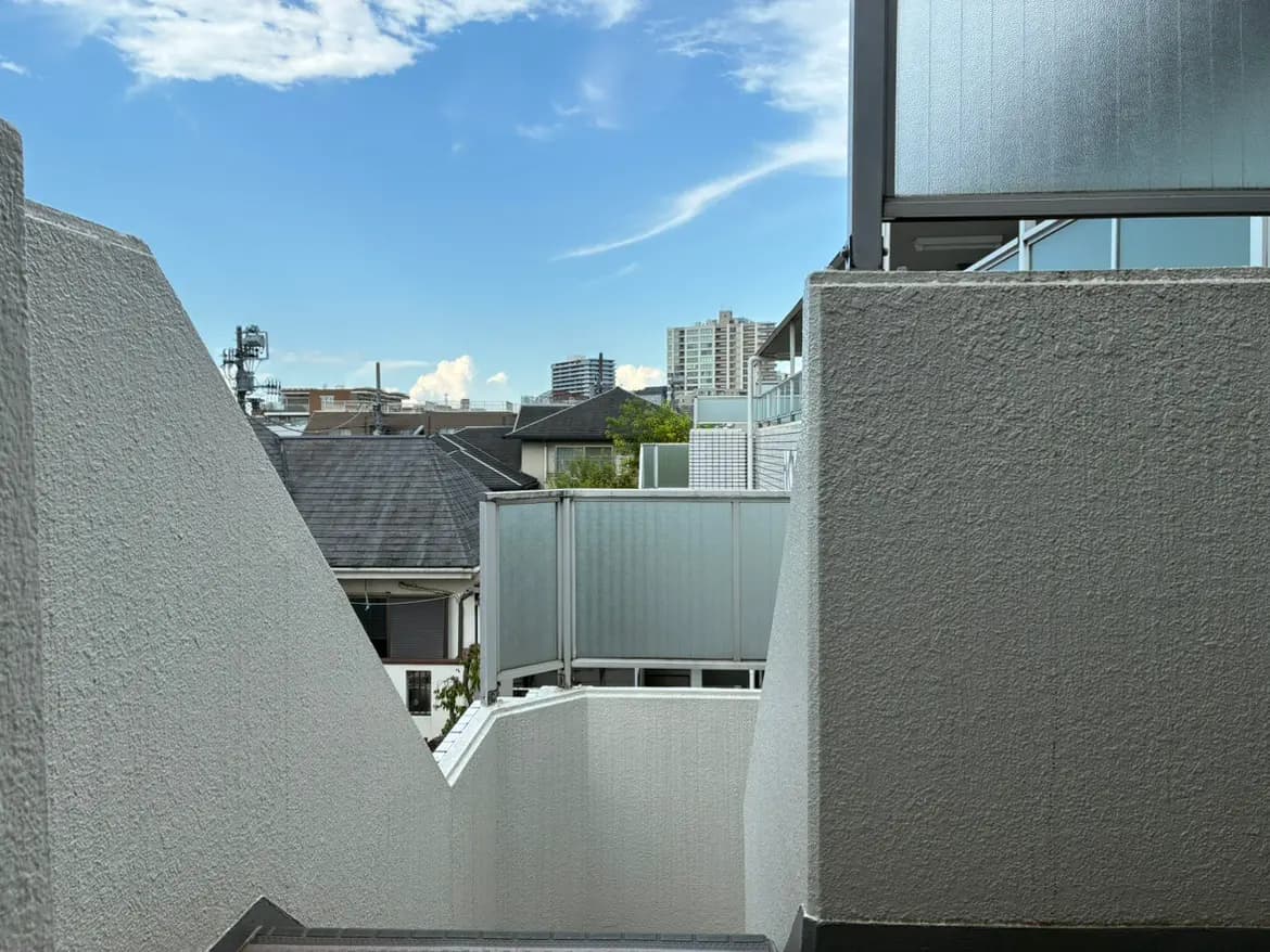- 明るい青空を背景にした白い壁に囲まれた階段、都市の景観が見える現代的な建物の外観