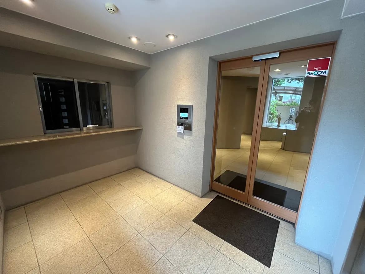 - モダンなエントランスホール、シンプルなデザインの受付カウンターと自動ドア、明るい照明とタイルフロアの空間