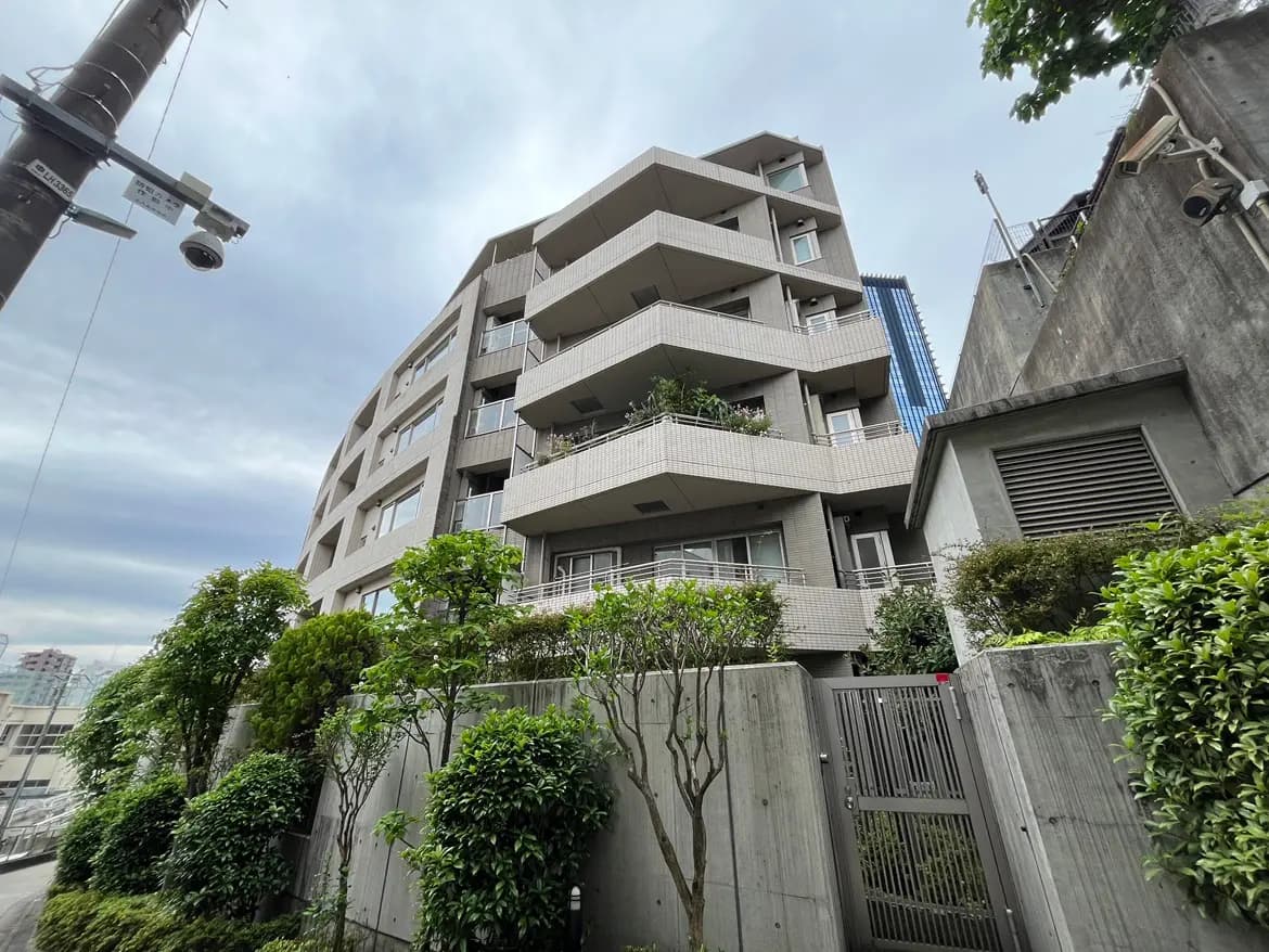 - 現代的なデザインのマンション、緑豊かな植栽とセキュリティカメラが配置された外観の風景
