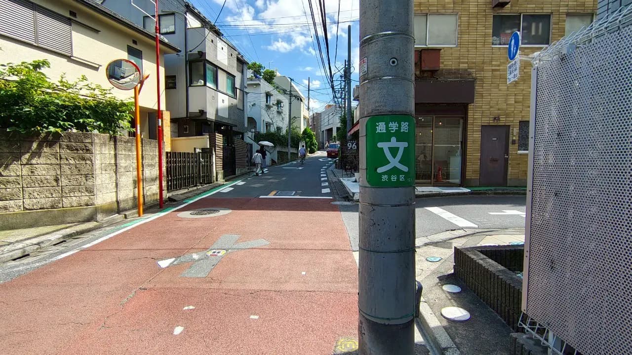 - 渋谷区の通学路の標識が立っている住宅街の風景、青空の下に続く穏やかな坂道