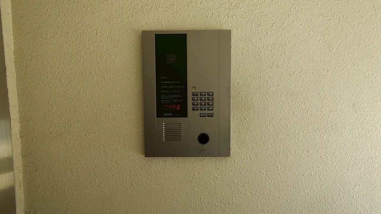 - SECOMのインターホン、壁に取り付けられたモダンなデザインで数字ボタンとカメラ機能付き