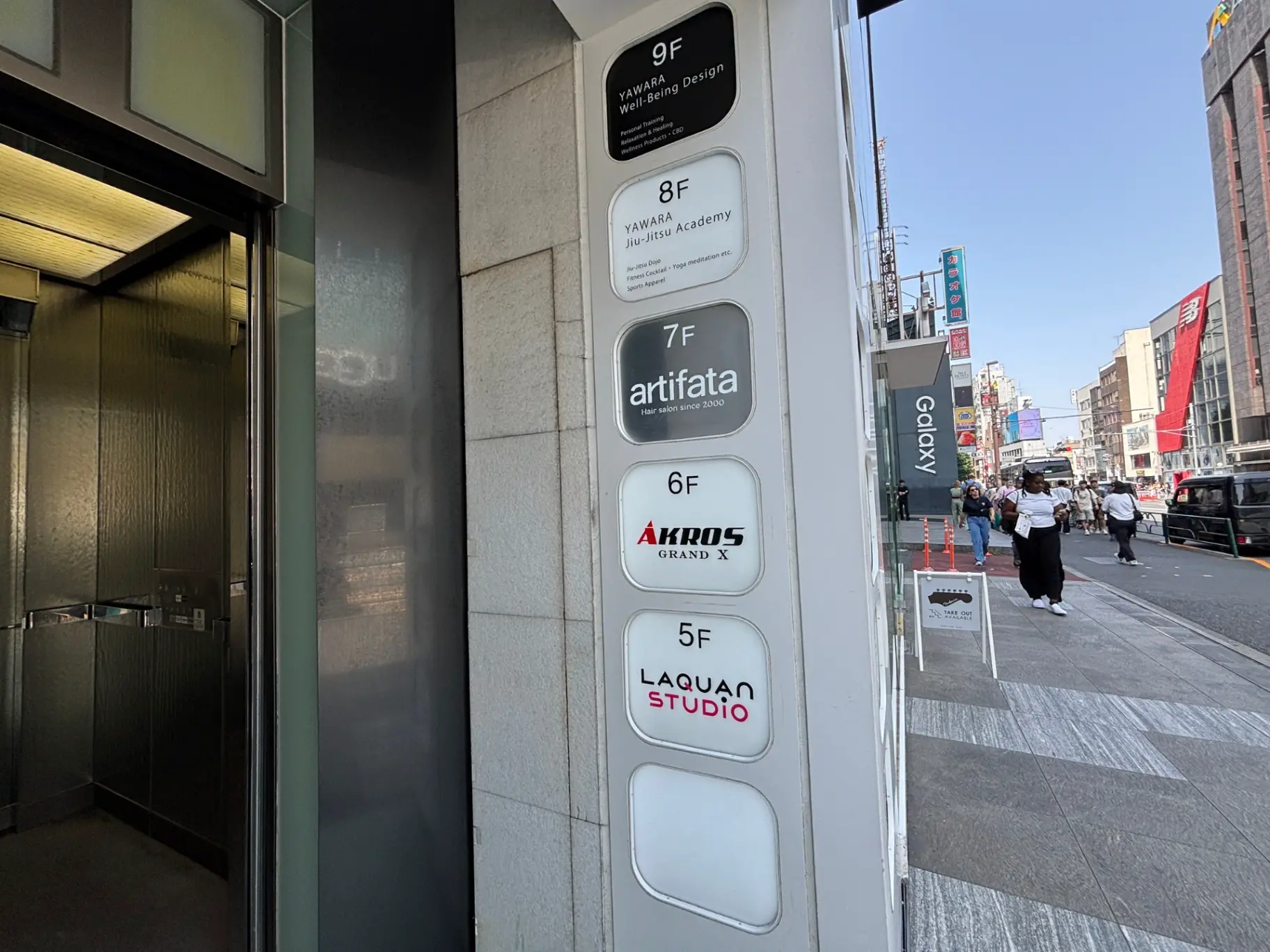 - ビルのエレベーター前に掲示された階数案内、様々な店舗名が表示されているサインボード