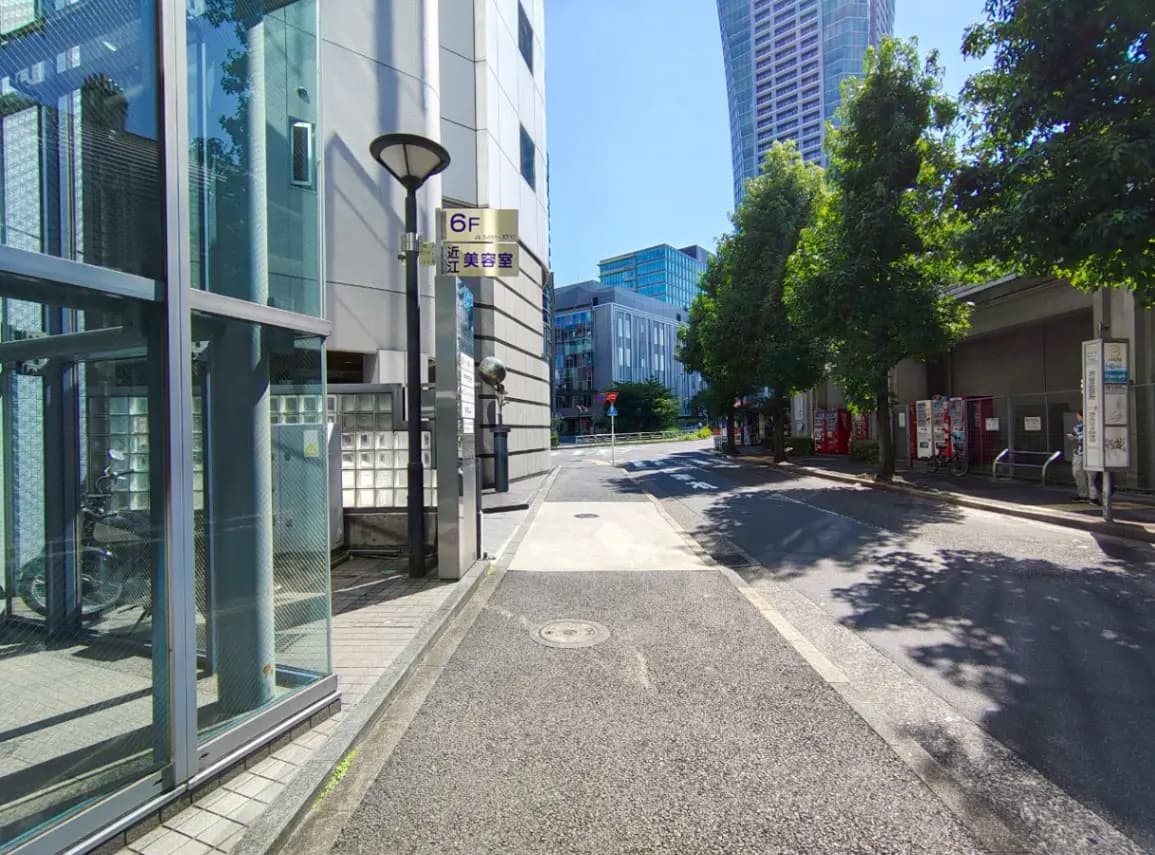 - 都市のビル街にある近江美容室の看板が見える街の風景、明るい青空と日射しの下での通りの様子