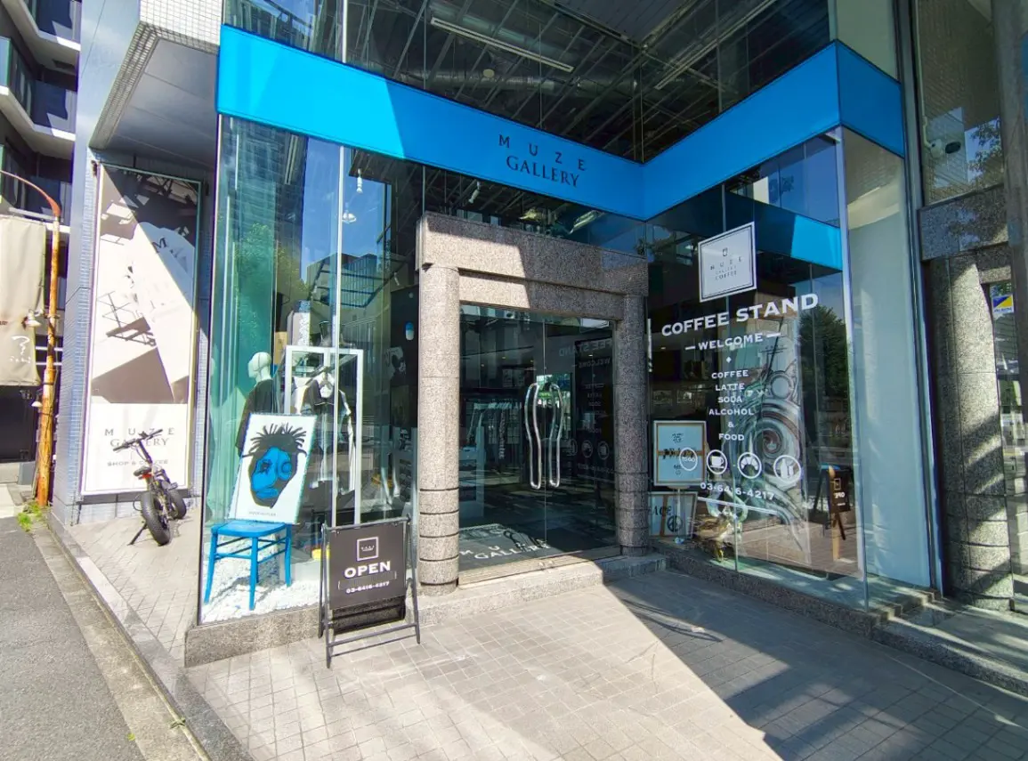 - 洗練された外観のMuze Gallery、ガラス張りの入口とアートの展示、コーヒースタンドが併設されたしゃれたギャラリーの景観