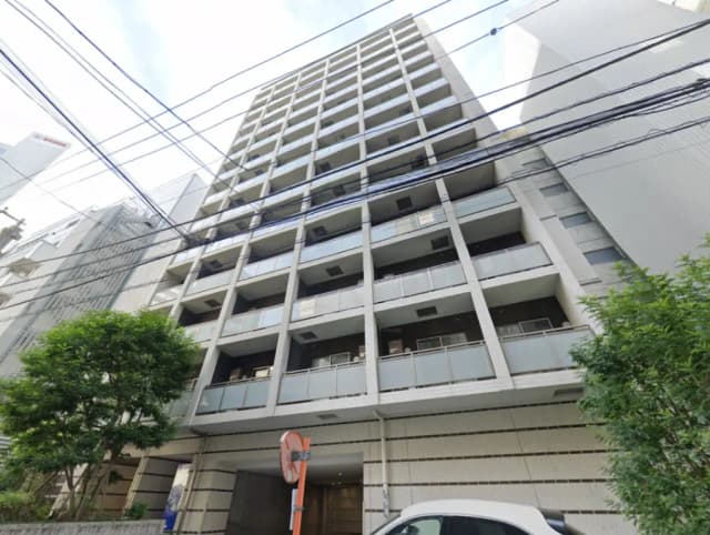 - モダンなデザインの高層マンション外観、バルコニーと植栽のあるエントランス、周囲の都市景観を背景にした写真