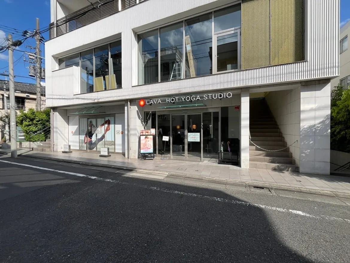 - LAVAホットヨガスタジオの外観、明るいガラス張りの入り口と階段、周囲の街並みとの調和が取れたデザイン