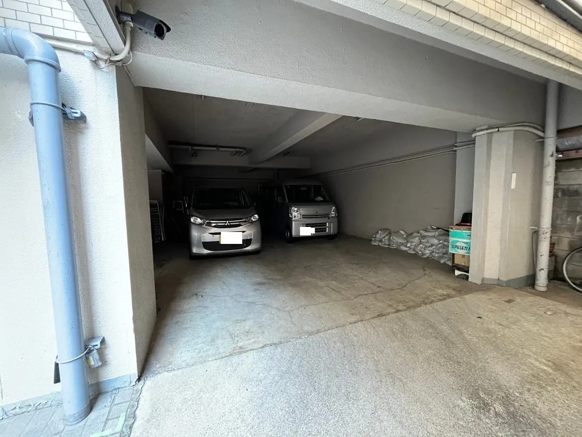 - 明るく広々としたガレージ、2台の車が停まっている、整理されたスペースと壁に置かれた荷物の様子