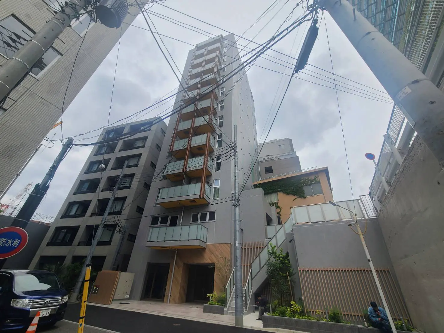 - 都市的なデザインのマンション外観、隣接する建物との対比、電線や街灯が配置された風景