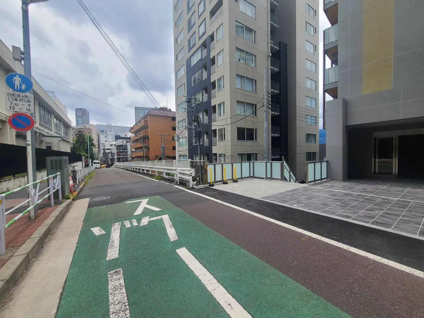 - 都市の景色を背景にした歩行者専用の道路と自転車レーン、近くに立ち並ぶ高層ビルと交通標識がある風景